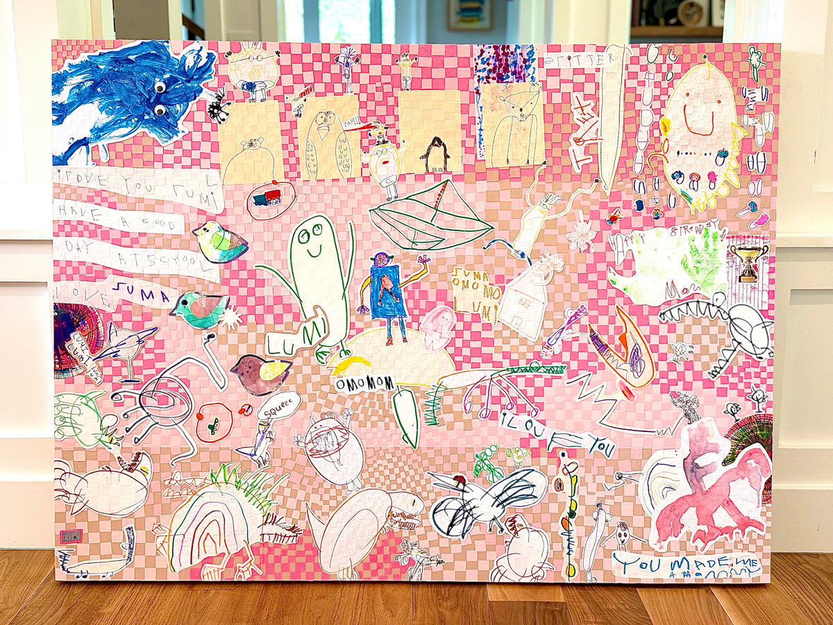 A finished custom collage on a pink checkered ground, with a child's pencil and marker drawings of animals and characters, resting on a wood floor.