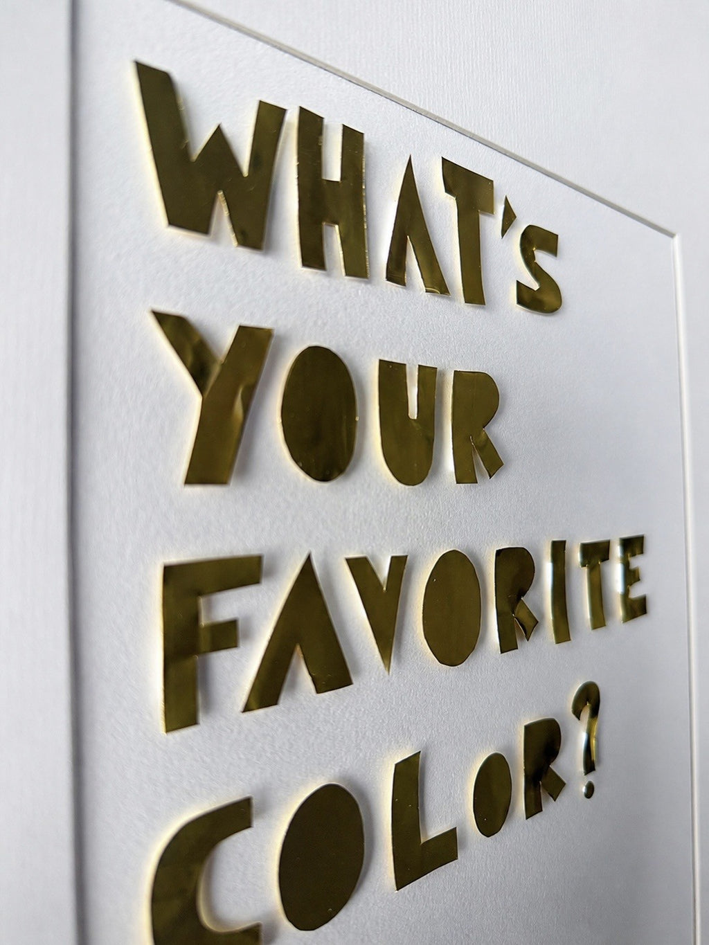 Close-up of gold metal letters throwing a soft shadow on cream cardstock