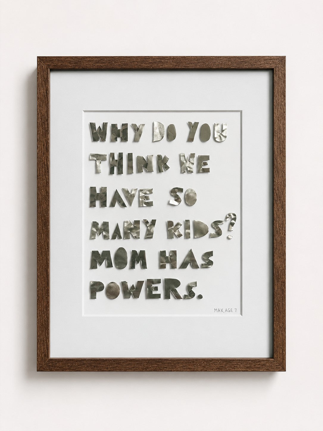 Quote piece in a brown oak frame, silver metal letters: Why do you think we have so many kids? Mom has powers.